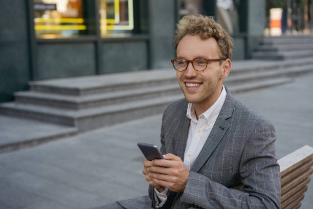 istock Smiling man wearing eyeglasses using mobile phone shopping online looking at copy space . Confident freelancer receive payment. Successful business 1344118738