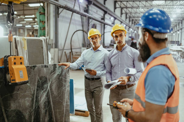 istock Employees in factory using crane to lift construction material 1344120900