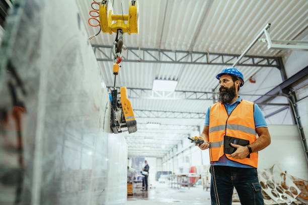 istock Employee in factory using crane to lift construction material 1344121261