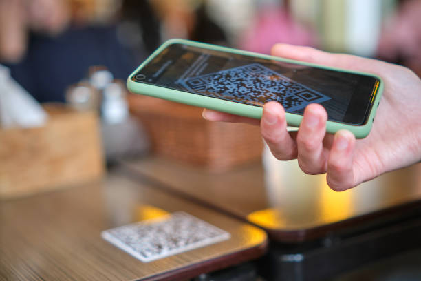 primer plano del huésped ordenando comida a mano en el restaurante mientras escanea el código qr con el teléfono móvil para el menú en línea. - dinner currency table business fotografías e imágenes de stock