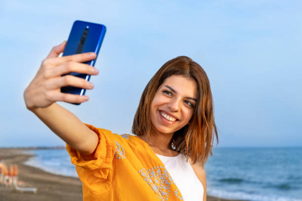 istock Smiling young brunette taking a selfie on the beach. 1344122899