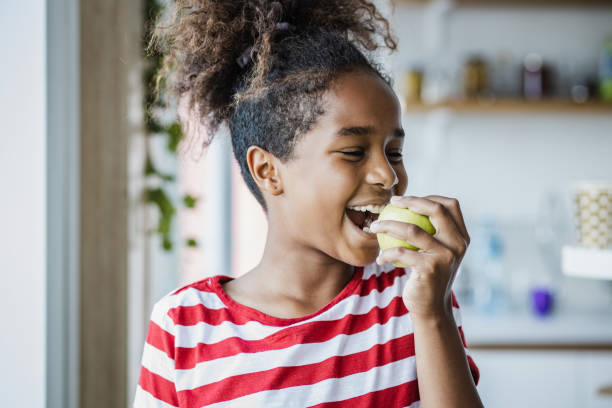 かわいい女の子がリンゴを食べる - child eating apple fruit ストックフォトと画像