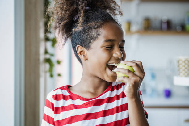 милая девушка ест яблоко - apple healthy eating eating black стоковые фото и изображения
