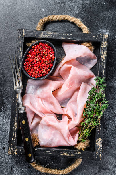 istock Thin sliced Smoked  pork ham in wooden tray. Black background. Top view 1344127781