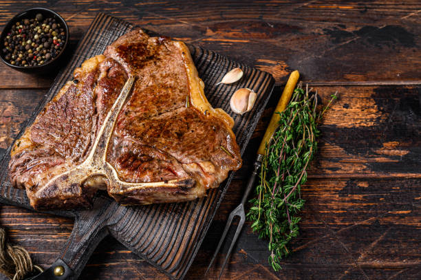 roast t-bone or porterhouse beef meat steak on a wooden cutting board. dark wooden background. top view. copy space - red meat meat dish grilled rare imagens e fotografias de stock