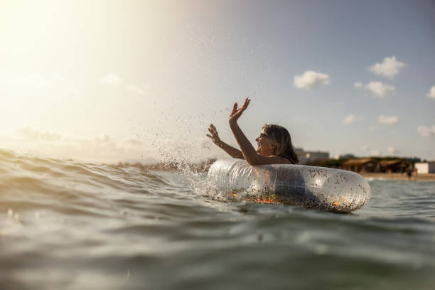 Happy senior woman enjoying floating ring in the sea stock photo