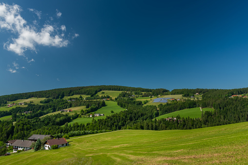 Pass near Niederer Schockl hill with green meadows and fences for cows in south Austria