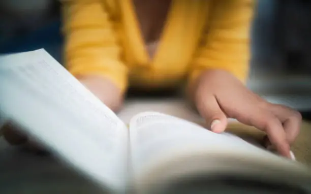 Photo of Woman in yellow, lying down, reading book