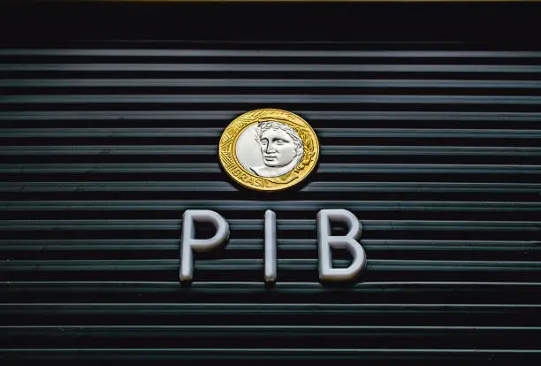 The word PIB ( gross domestic product ) formed in a lettered board with a Brazilian coin. Brazilian Portuguese language.