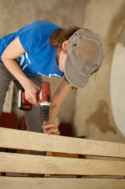 istock Skilled young female worker is using power screwdriver drilling during construction wooden bench gender equality, feminism, do it yourself concepts 1344131898