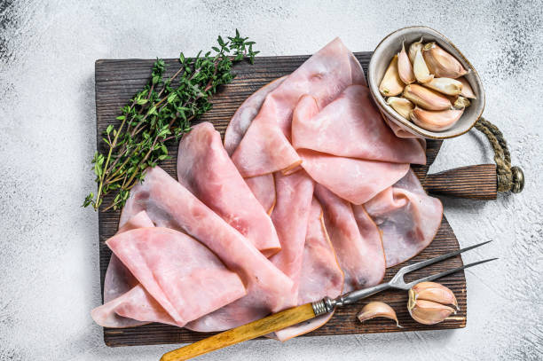 istock Ham Thin sliced on wooden cutting board with herbs. White background. Top view 1344133663