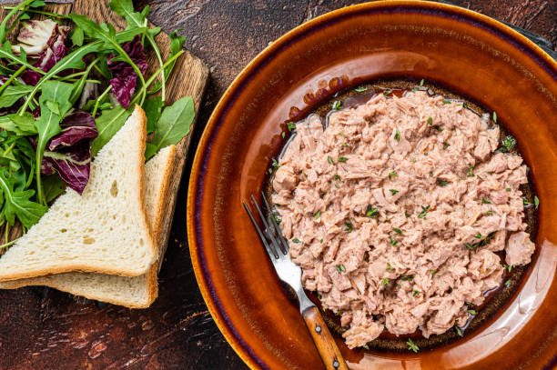 istock Tuna canned fish with bread and salad. Dark background. top view 1344134432
