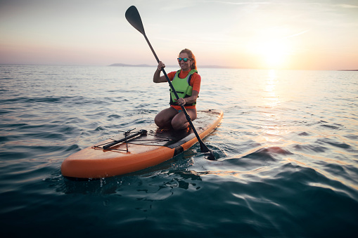 Woman practicing paddle on a sunset sea