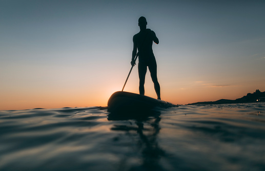 Low angle view of  man silhouette paddling SUP board.