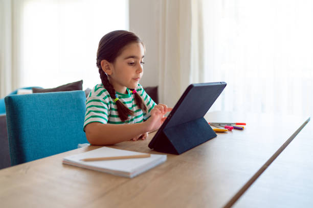 little girl taking online courses in living room - child computer laptop little girls imagens e fotografias de stock