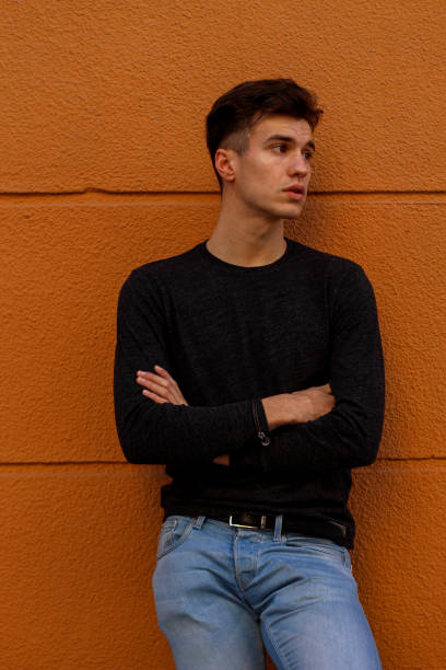 istock Vertical portrait of young guy waiting on an orange wall 1344138800