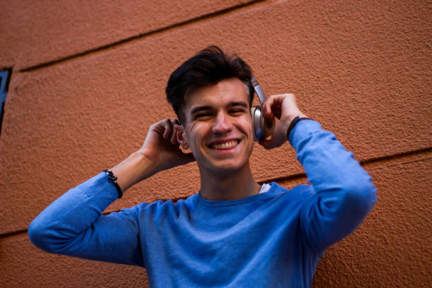 istock young smiling guy with headphones on orange wall 1344138854