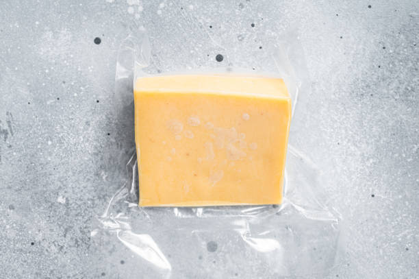 istock Organic Sharp Cheddar Cheese in vacuum packaging. Gray background. Top view 1344139102