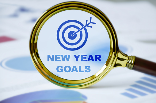 New year goals. New year resolution. Business target icon and new year goals in magnifying glass with business graphics