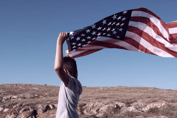 istock A boy holding waving US flag, beeng a patriot concept 1344143823
