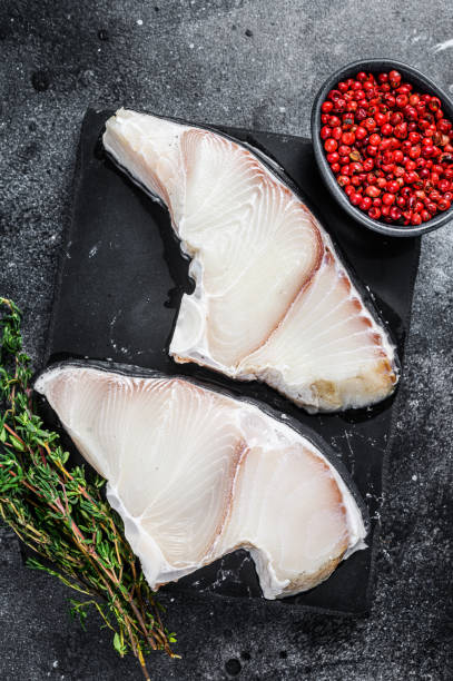 istock Raw Shark fish steaks on a board. Black background. Top view 1344147719