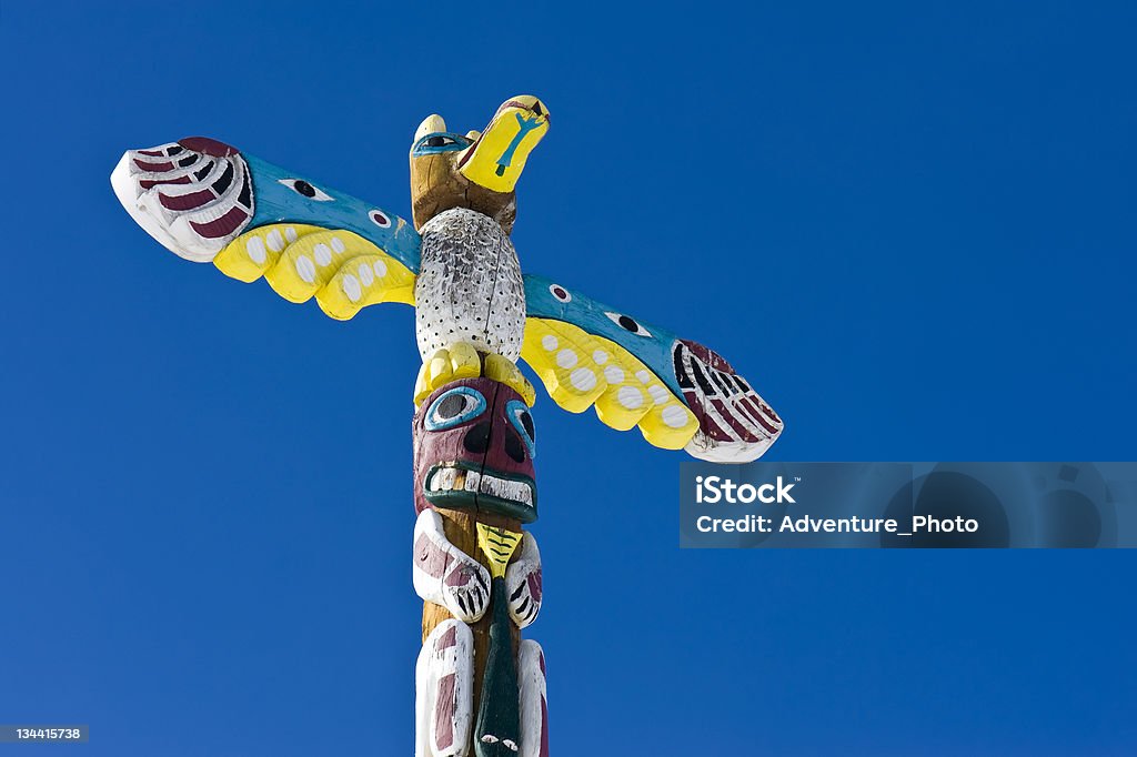 Totem Pole Totem Pole.  Native American Indian totem pole outdoor with clear blue sky backdrop.  Captured as a 14-bit Raw file. Edited in ProPhoto RGB color space. American Culture Stock Photo