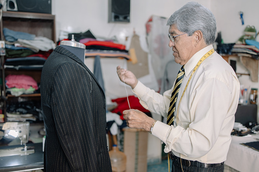 mature Mexican tailor working on local business