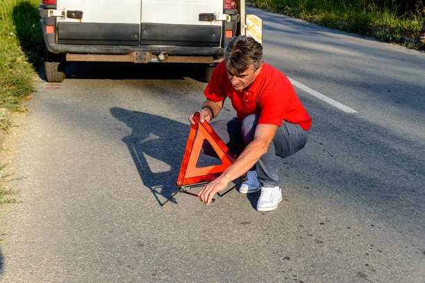 un homme a eu un accident de voiture et met un panneau d’avertissement triangulaire. - reflector danger warning triangle vehicle breakdown photos et images de collection