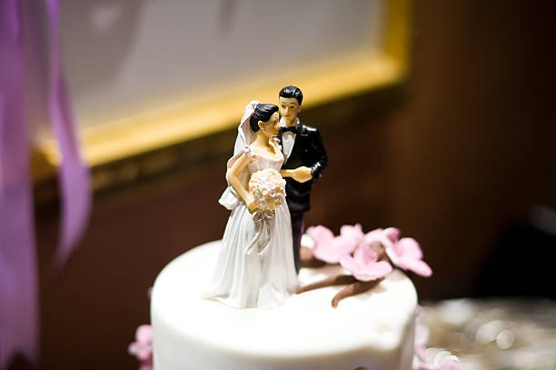 Wedding cake with couple figurines against white background