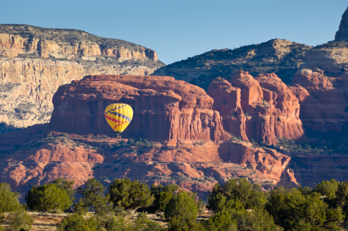 Hot Air Balloon Floating Through Scenic Canyon.  Single hot air balloon flying low in scen red rock canyon country outside Sedona, Arizona USA.  Converted from 14-bit Raw file.  sRGB color space.