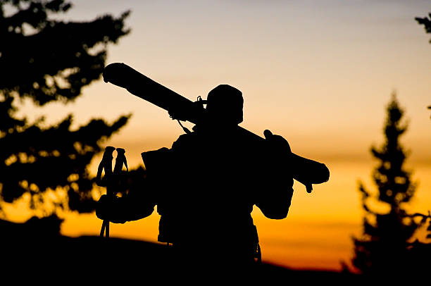 Man Hikes Into Sunset with Skis Over Shoulder