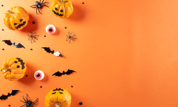 istock Halloween decorations made from pumpkin, paper bats and black spider on orange background. Flat lay, top view with copy space for text. 1344170698