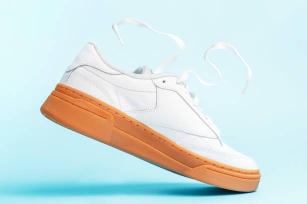 istock Levitation of white sneaker close-up on blue background. 1344173845