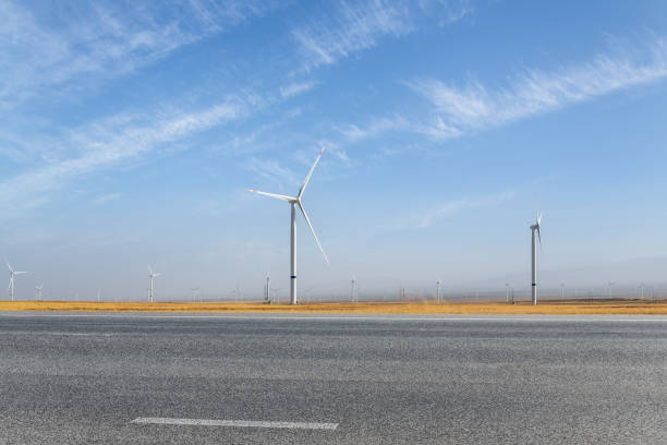 istock empty asphalt road and wind farm 1344180374