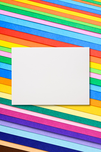Overhead shot of blank white paper on multi colored paper.