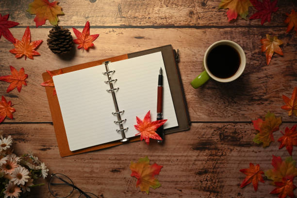 istock Above view empty notebook, coffee cup and autumn maple leaves on wooden background. 1344198133