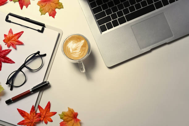 istock Top view laptop computer, coffee cup, glasses and autumn maple leaves on white background. 1344198169
