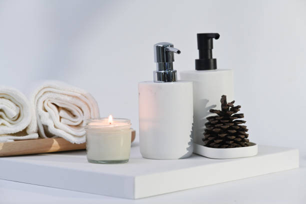 Spa composition with burning candle, towels and bottles on white background. Spa treatment and relax concept.