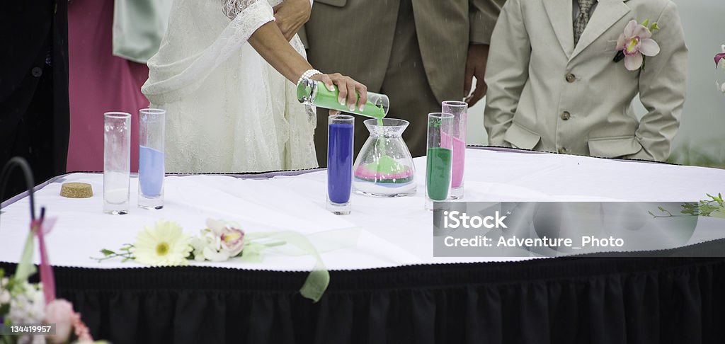 Bride and Groom Pouring Sand as Sign of Commitment Bride and Groom Pouring Sand as Sign of Commitment.  Colored grains of sand symbolize families coming together.  Converted from 14-bit RAW file.  ProPhoto RGB color space. Bride Stock Photo