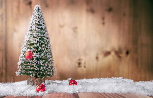 Little Christmas Tree on Wooden Table Little Christmas Tree on Wooden Table with Fake Snow and Red Ornaments artificial snow stock pictures, royalty-free photos & images