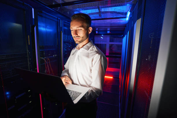 istock System technician running diagnostic of server racks with laptop 1344207129