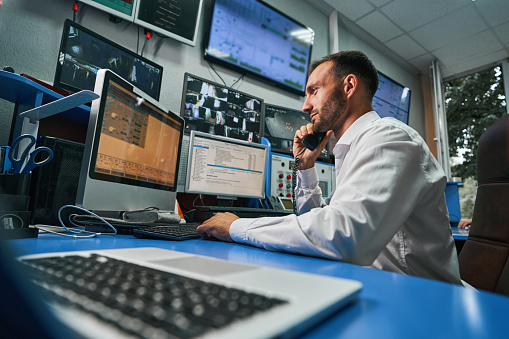 Data center operations professional talking on the phone while monitoring network stability through computer