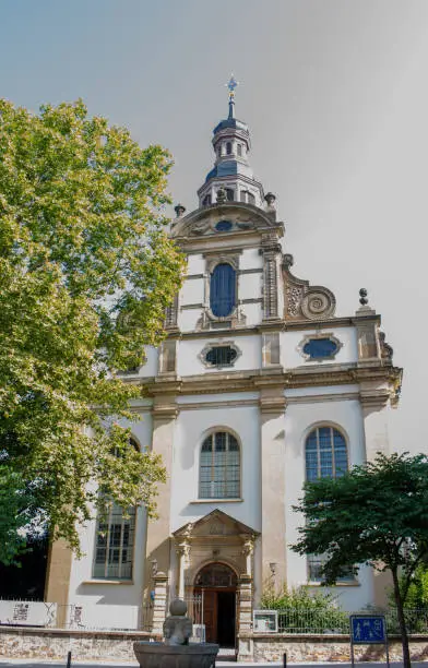 This image shows a close, low angle view of the exterior Baroque architecture on Trinity Church, a Protestant church in Speyer, Germany, which is also called Dreifaltigkeitskirche.