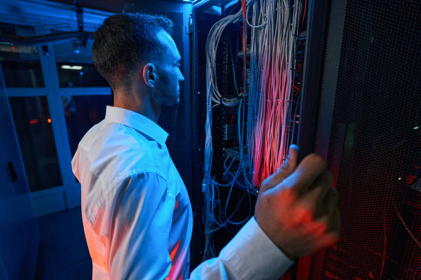 istock Man inspecting cables and wires of network equipment 1344208657