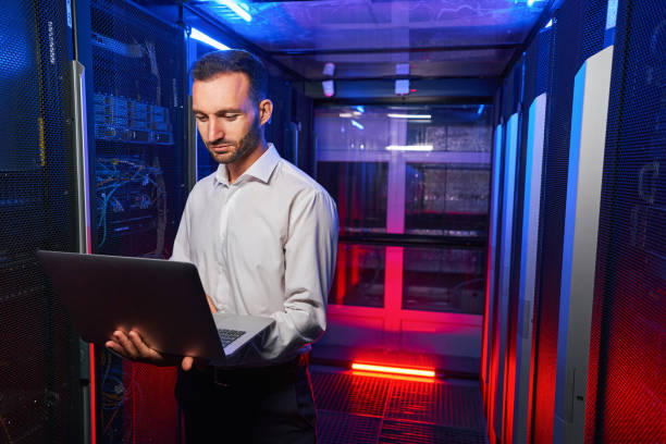 istock Bearded confident maintenance engineer in white shirt is working in database center 1344208939
