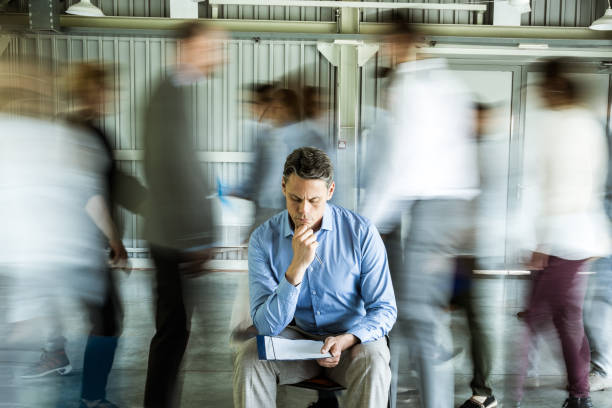 istock Pensive businessman reading reports surrounded by his colleagues in blurred motion. 1344209255