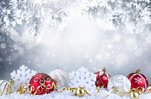 Festive background Christmas decoration with red and white Christmas balls, snowflakes in snow and snow covered fir branches, copy space.