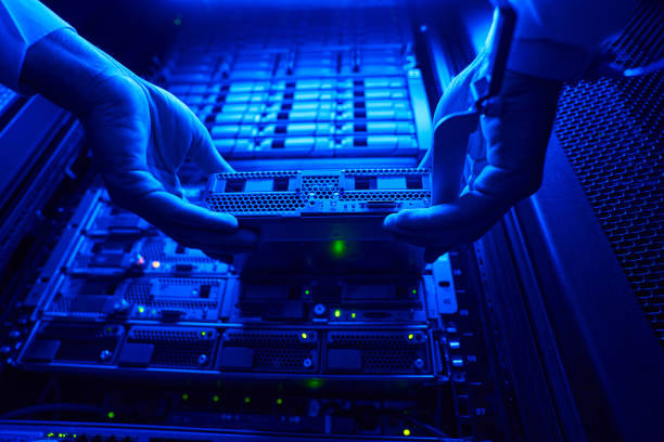 Unrecognized it engineer find and troubleshooting server computer in data center Close up low angle portrait of man hands holding HDD disk while connected it to optic port spatholobus suberectus dunn stock pictures, royalty-free photos & images