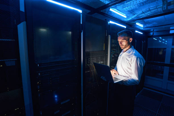 istock Professional system administrator clicking on laptop near server cabinets 1344210793