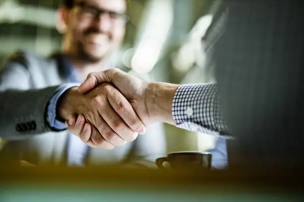 Close up of unrecognizable businessmen shaking hands on a meeting in the office. Copy space.